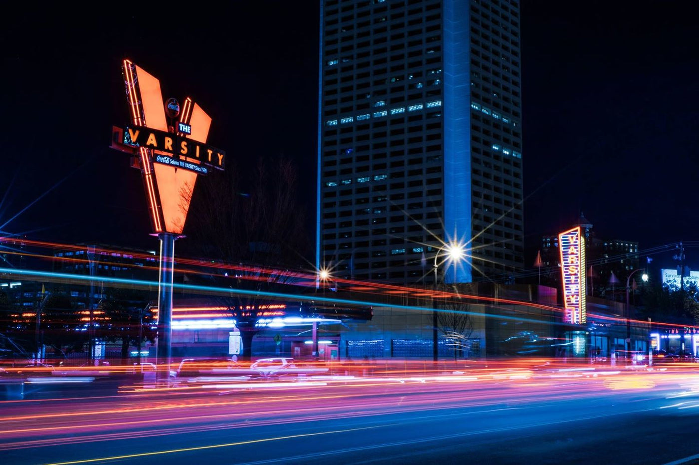 Image of the Varsity at night with vibrant colors from neon and cars passing by.  Landing image for all products list.